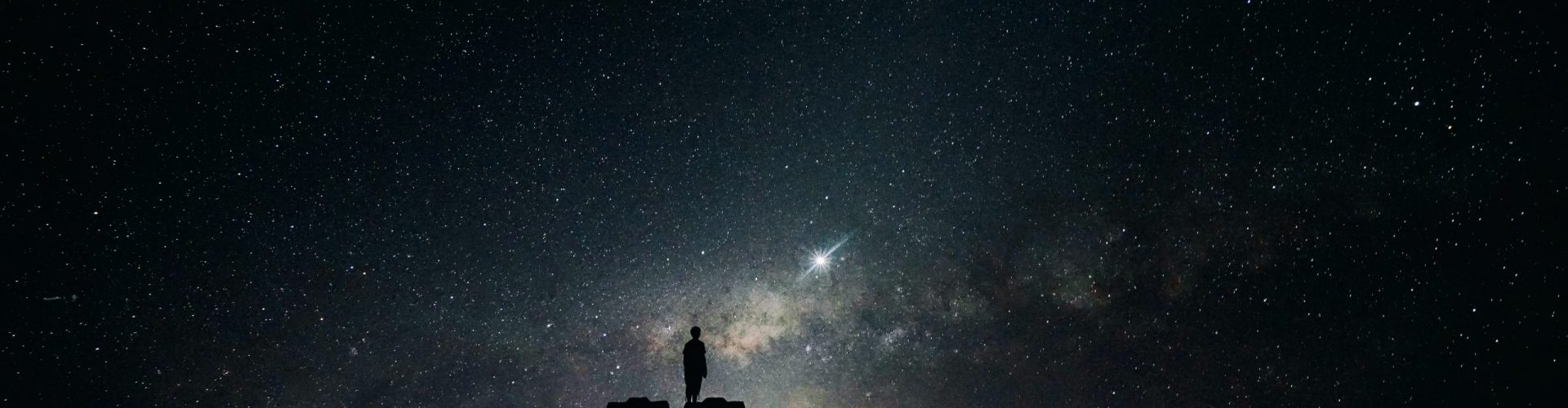 Silhouette of man standing on car in front of night sky